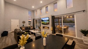 Un salón amplio con chimenea, televisor de pantalla plana y comedor con una mesa grande y sillas.
