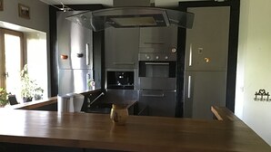 Ett modernt kök med vitvaror i rostfritt stål, en bänkskiva i trä och en inbyggd ugn.