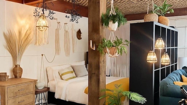 A modern bedroom with a bed, bedside tables, a wardrobe, and hanging plants.