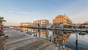 A wooden pier extending into calm water, with multi-story buildings on the opposite bank. - Renovated 1st Fl 2BR/2BA, priv patio! Indoor/outdoor Pool; steps to BEACH & Dine (Ocean City)