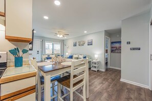 Un comedor con mesa y sillas de madera, ventilador de techo y decoración en la pared.