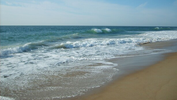A beach with waves approaching the shore. - Renovated 1st Fl 2BR/2BA, priv patio! Indoor/outdoor Pool; steps to BEACH & Dine (Ocean City)