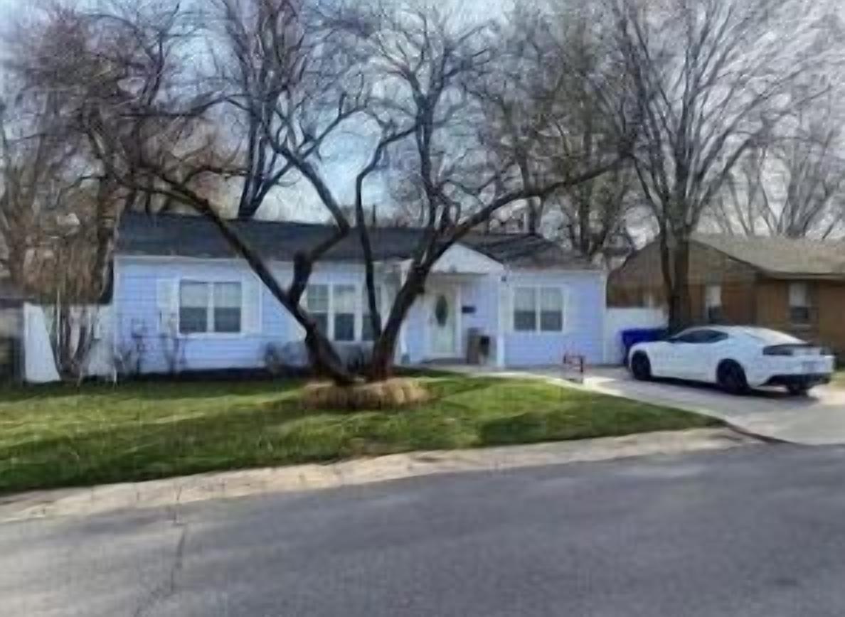 A residential house with a front yard, a driveway, and a parked white car.