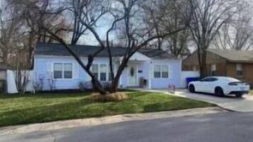 A residential house with a front yard, a driveway, and a parked white car.