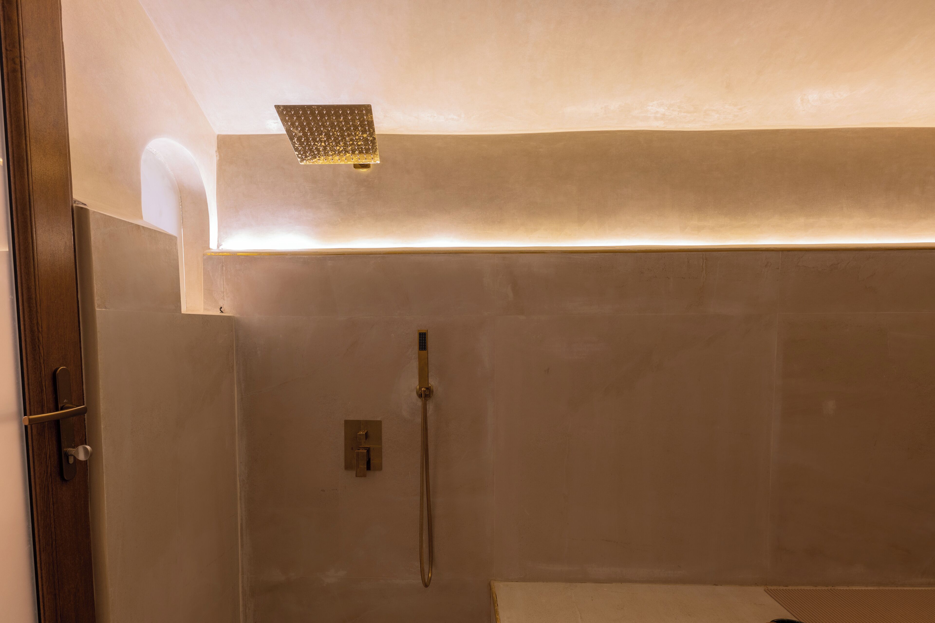Un baño moderno con ducha, una lámpara empotrada en la pared y una puerta.