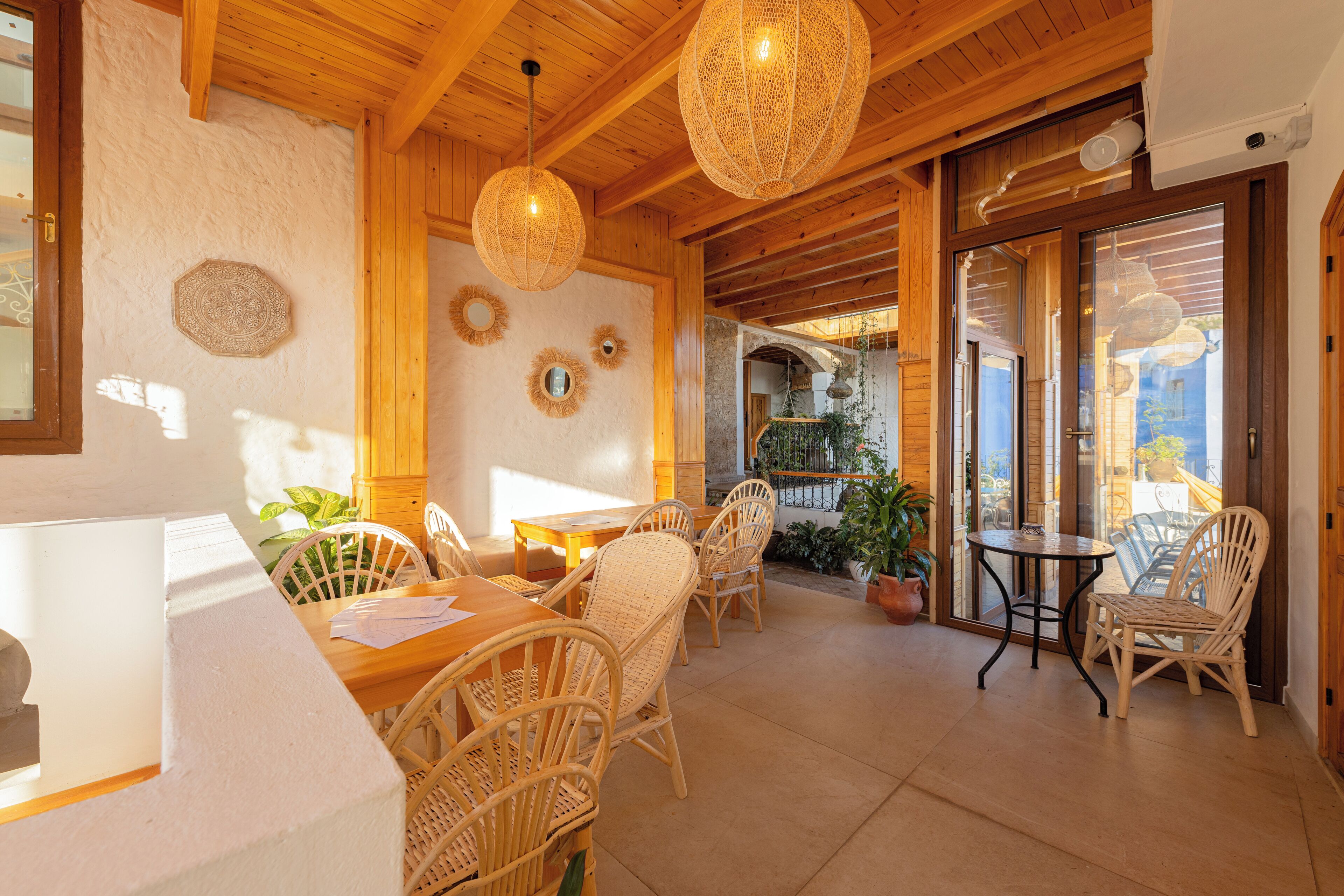 A wooden interior with wicker furniture, a dining area, and a view through a glass door.