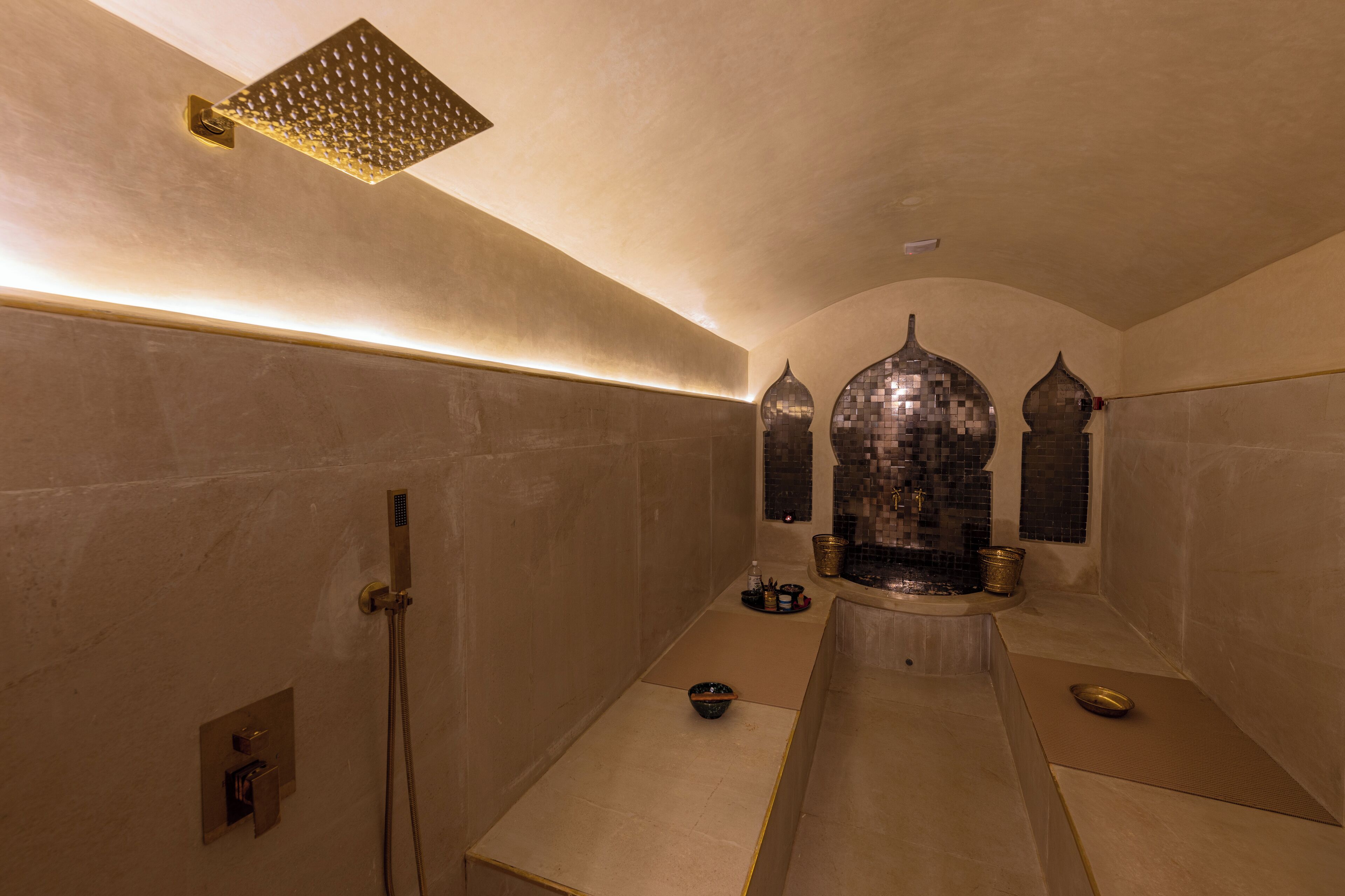 A modern bathroom with a walk-in shower, a large mirror, and a decorative fountain.