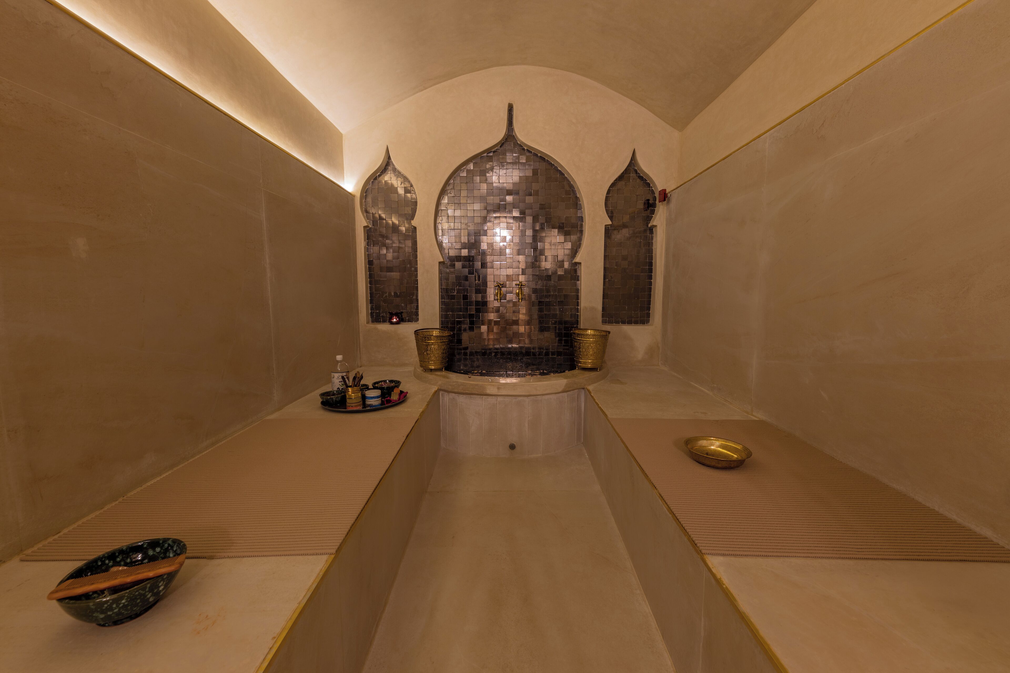 A spa room with a central hot tub, two side alcoves, and a long bench.