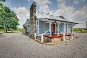 Een laag huis met een stenen schoorsteen, lichtblauwe gevelbekleding en een rode veranda.