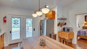 Une cuisine avec des meubles de rangement en bois, un four à micro-ondes posé sur un meuble en bois, et un grand îlot central agrémenté d’un élément décoratif.