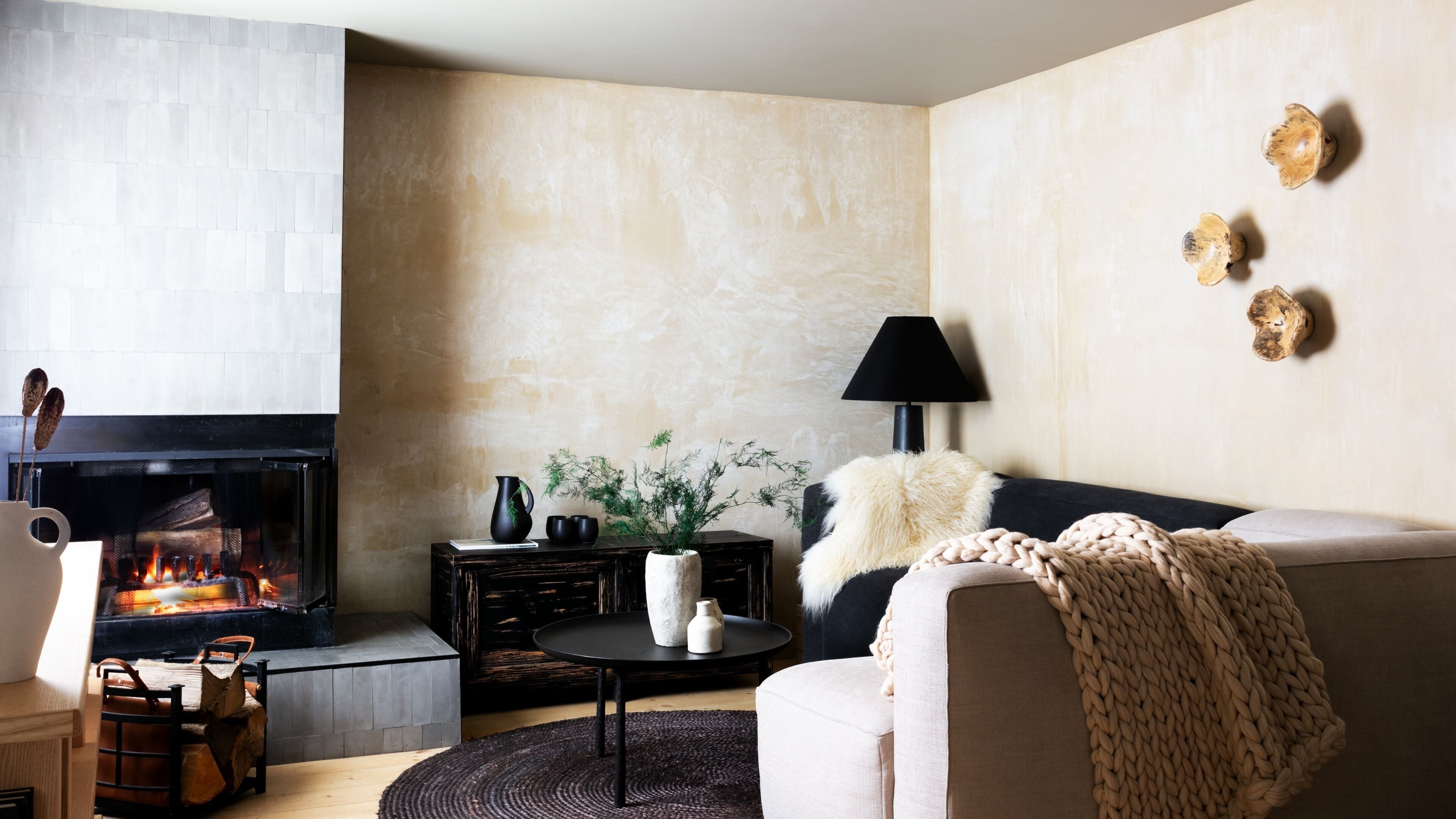 Un salon moderne avec une cheminée, un canapé, une table basse et des œuvres d’art décoratives au mur.