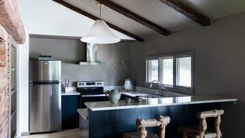 Una cocina con un refrigerador de acero inoxidable, un horno empotrado y una isla grande con un lavamanos.