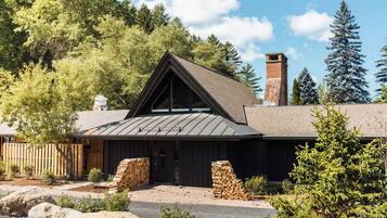 A rustic cabin with a sloped roof, stone foundation, and a chimney.