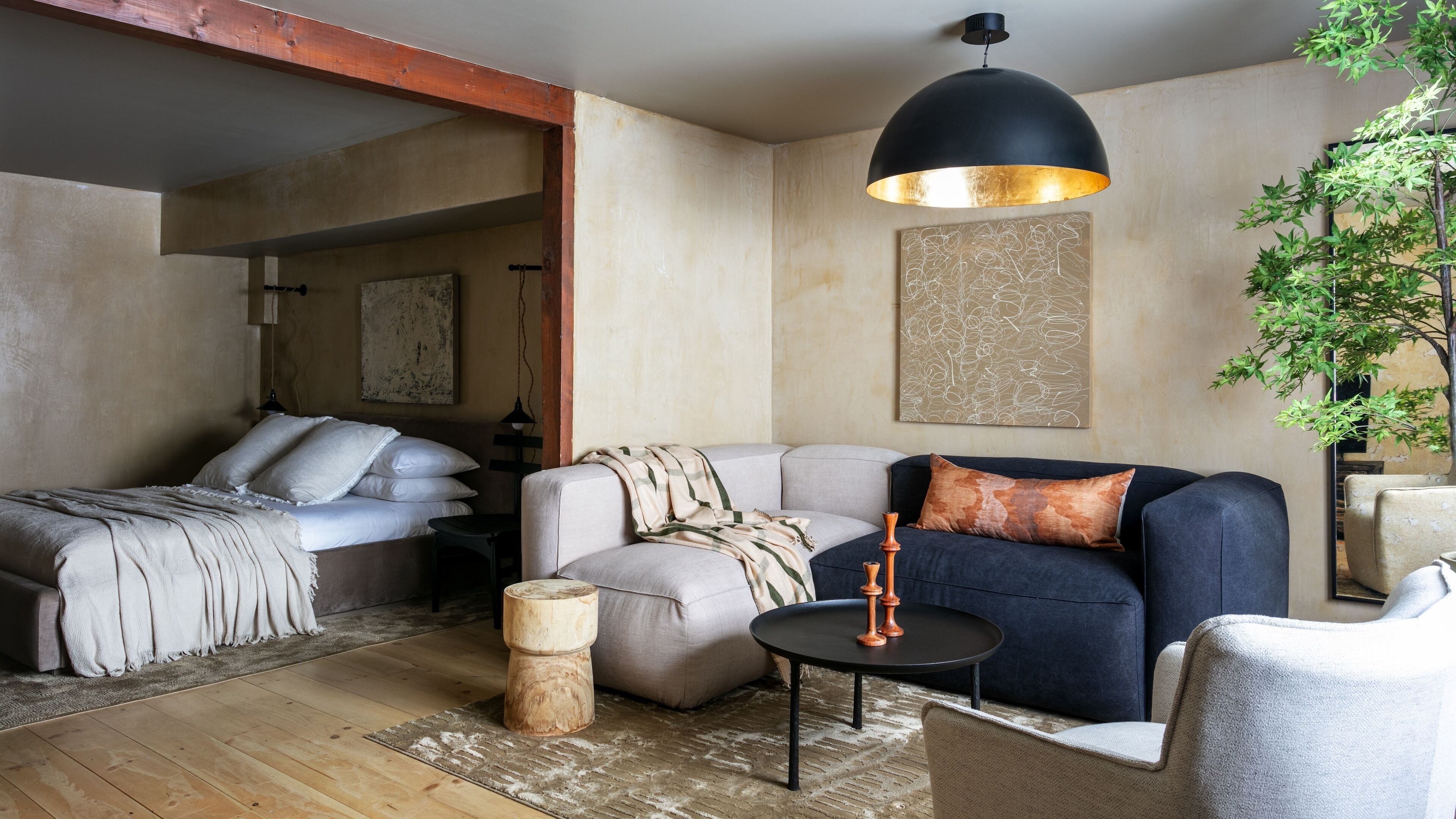 Una sala de estar moderna con cama, sofá y una mesa de centro redonda.