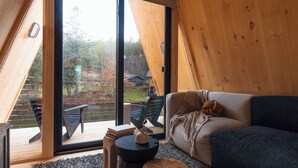 A cozy interior with a sofa, a small table, and a view of an outdoor deck. - AWOL Stowe (Stowe)