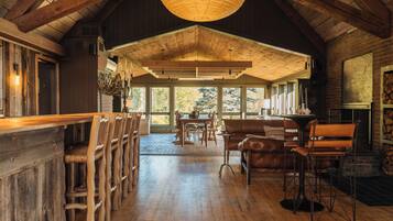 Un intérieur spacieux avec un plancher en bois, un plafond haut et de grandes fenêtres offrant une vue sur l’extérieur.