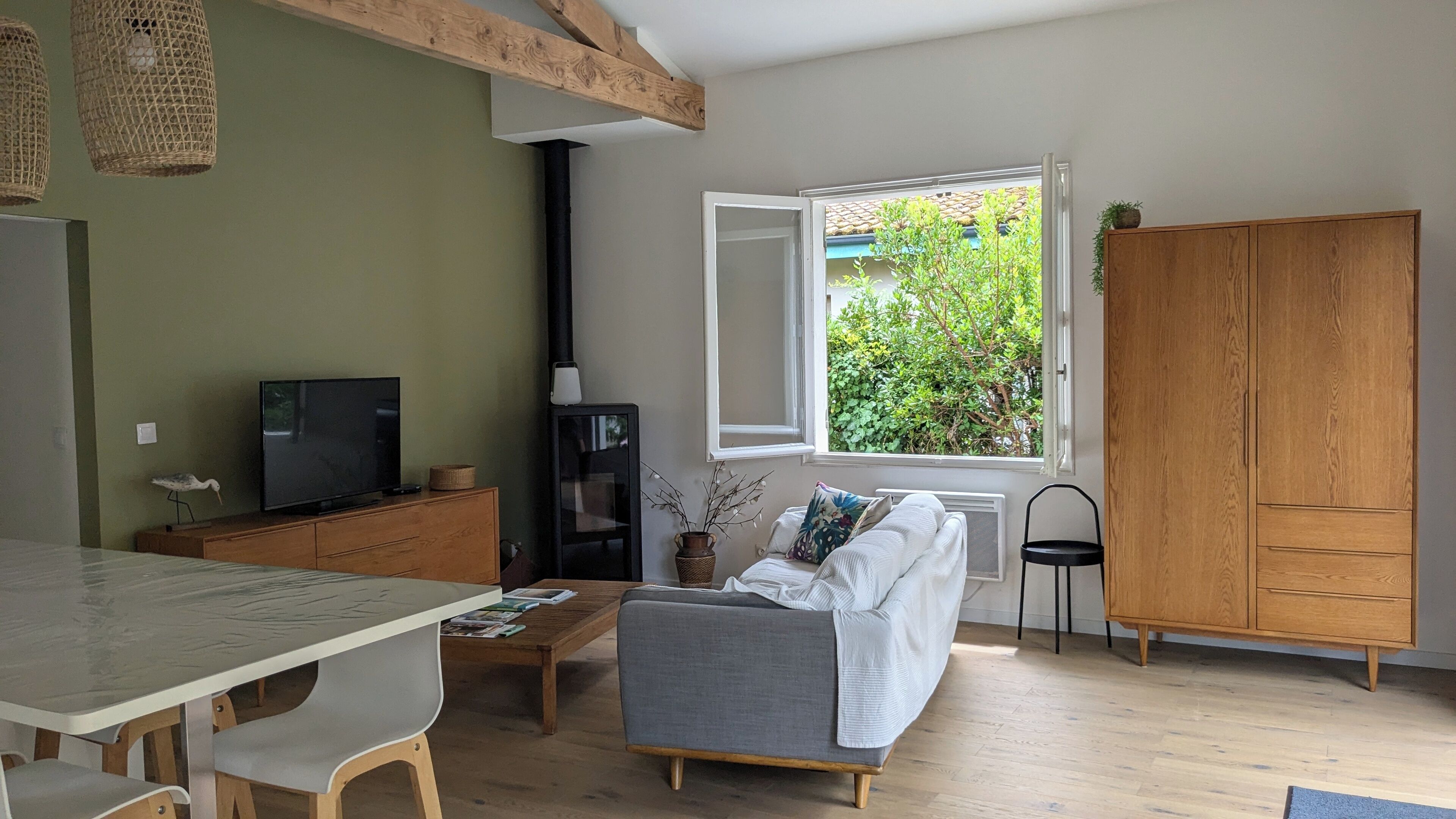 Un salon comprenant un canapé, une table basse, un téléviseur et une fenêtre donnant sur un paysage verdoyant.