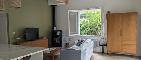 Una sala de estar con un sofá, una mesa de centro, un televisor y una ventana con vistas a zonas verdes.