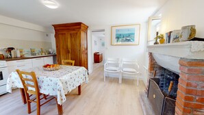 A cozy kitchen with wooden cabinets, a dining table with chairs, and a brick fireplace.