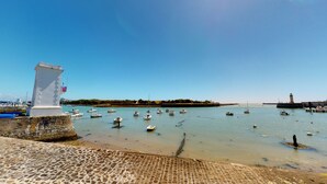 A harbor with boats, a lighthouse, and a stone monument.