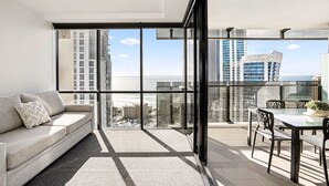 Eine moderne Wohnung mit Balkon, einer Couch und einem Essbereich mit Blick auf Stadt und Meer.