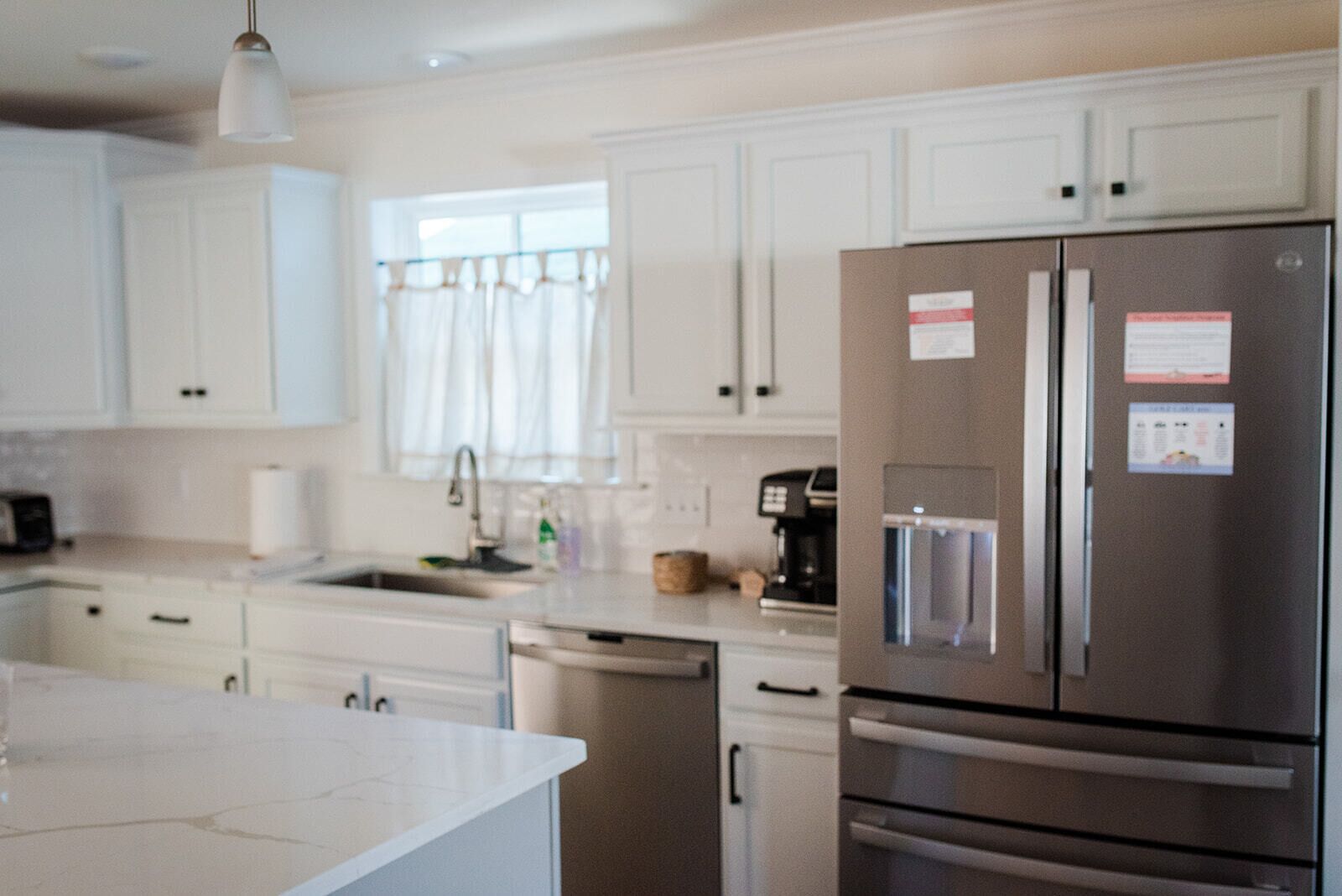A modern kitchen with white cabinets, stainless steel appliances, and a built-in dishwasher.