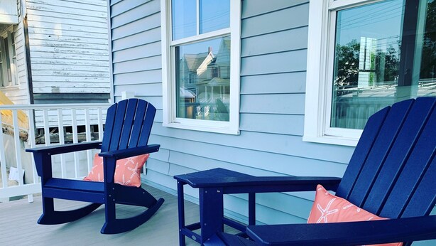 Dos sillas Adirondack con almohadones de estrella de mar en una terraza de madera.