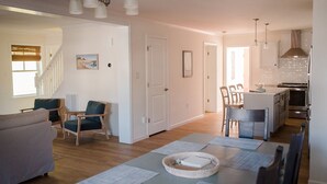 Amplia sala de estar con sofá, sillones, una mesa de comedor y una zona de cocina con estufa y refrigerador.