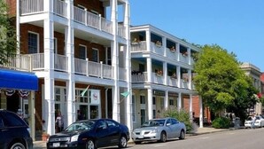 Un edificio de varios pisos con balcones, vista a la calle y coches aparcados.