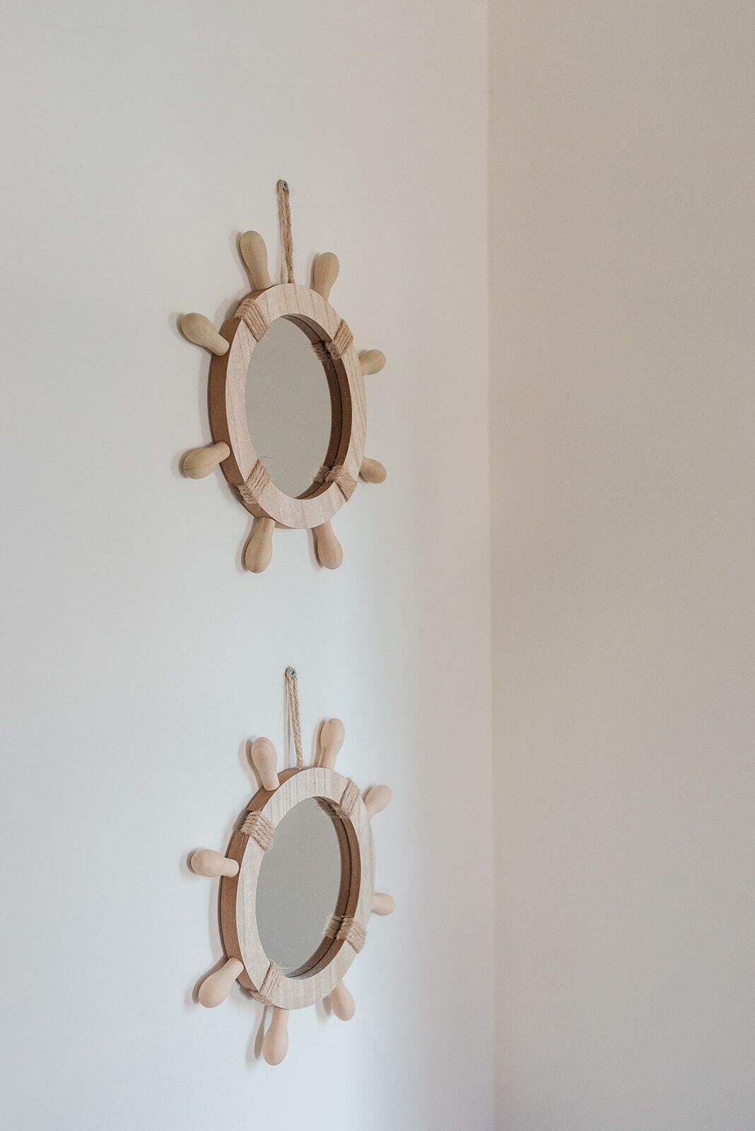 Two wooden wall mirrors with rope handles.