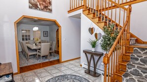 Un vaste espace de vie agrémenté d’un escalier en bois, d’un coin repas et d’un tapis rond.