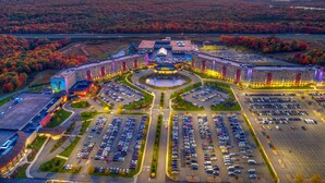 Vue aérienne d’un hôtel doté d’une cour intérieure, de plusieurs parkings et entouré d’un paysage automnal.
