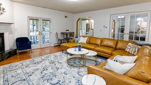 Un salon avec un canapé en cuir marron, un fauteuil bleu, une table basse ronde et un tapis à motifs.