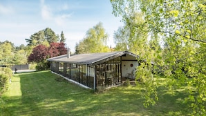 Einbungalow mit einer großen Glasveranda, einem Schornstein und einer kleinen Veranda.