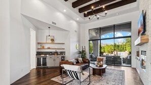 A spacious living area with a large window, a fireplace, and a cozy seating arrangement. - Scottsdale Paradise- POOL, Spa, Pickleball/Basketball, Fire Pit & Great HIKING! (Scottsdale)