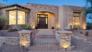 A modern house with a stone facade, large windows, and a welcoming entrance with steps. - Scottsdale Paradise- POOL, Spa, Pickleball/Basketball, Fire Pit & Great HIKING! (Scottsdale)