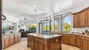 A spacious kitchen with a large island, wooden cabinets, and a view of the outdoors. - Scottsdale Paradise- POOL, Spa, Pickleball/Basketball, Fire Pit & Great HIKING! (Scottsdale)