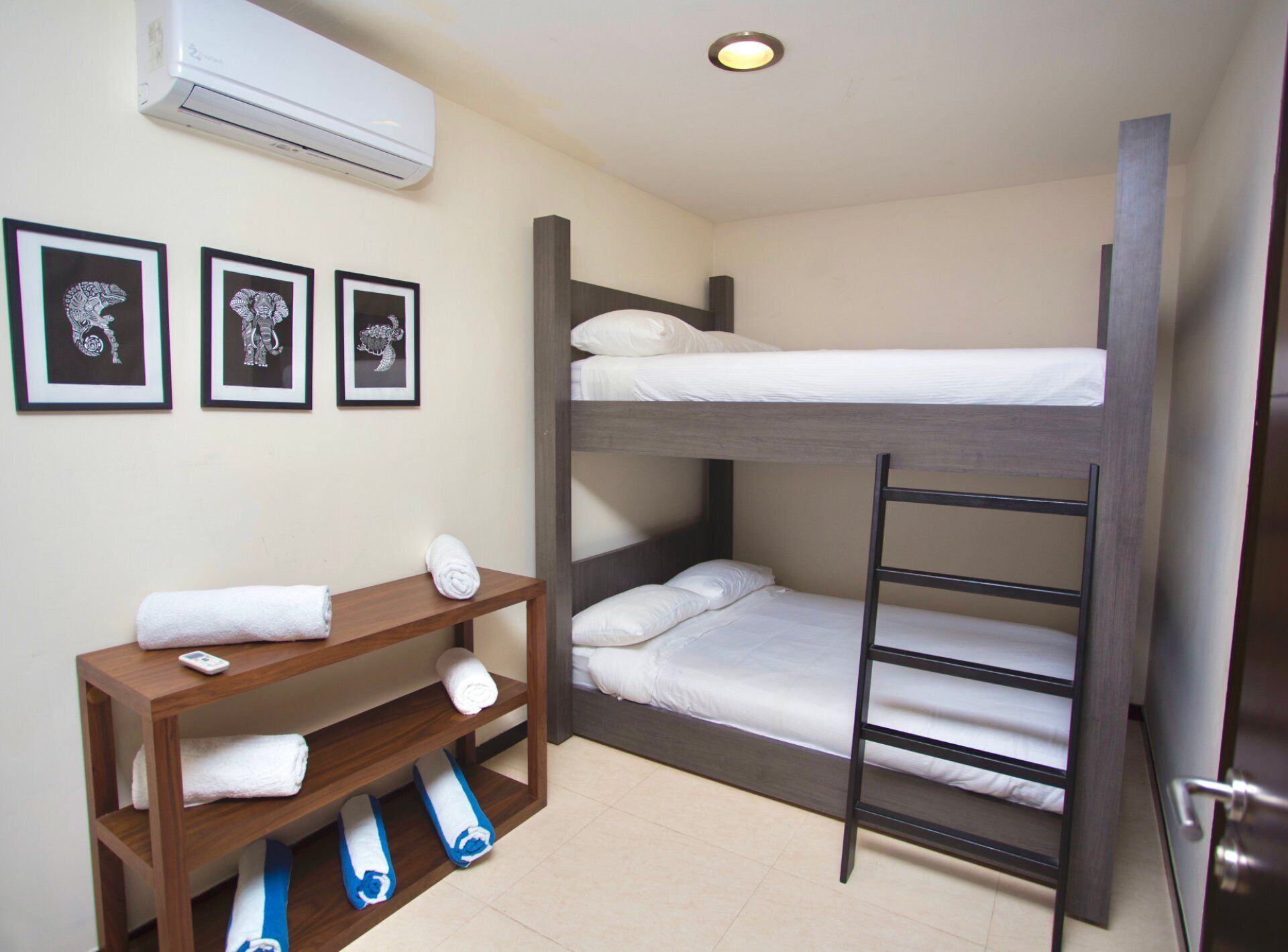 A bunk bed room with a wooden bench, a phone, and towels.