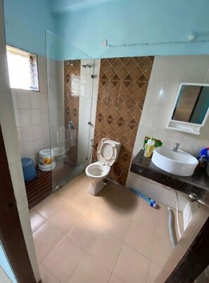 Bathroom features a toilet, sink, and shower area with a glass door.