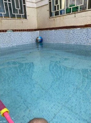 Guests can enjoy a refreshing swim in the pool surrounded by a building with a window.