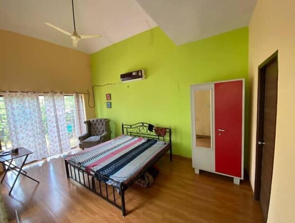 Relax in this serene space with a comfortable bed against a soothing wall, a stylish wardrobe, and a ceiling fan overhead.