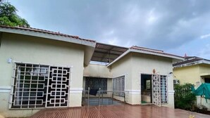 Een gebouw met een overdekte patio, metalen hekken en een betonnen muur.