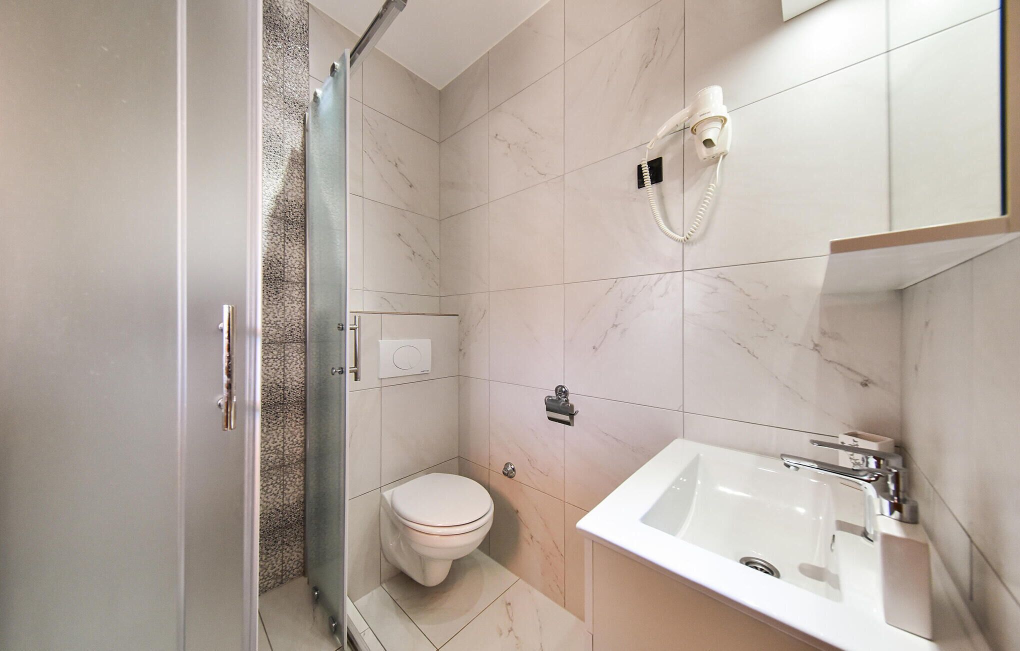 Ein modernes Badezimmer mit Duschkabine aus Glas, Toilette und Waschbecken mit Spiegel.