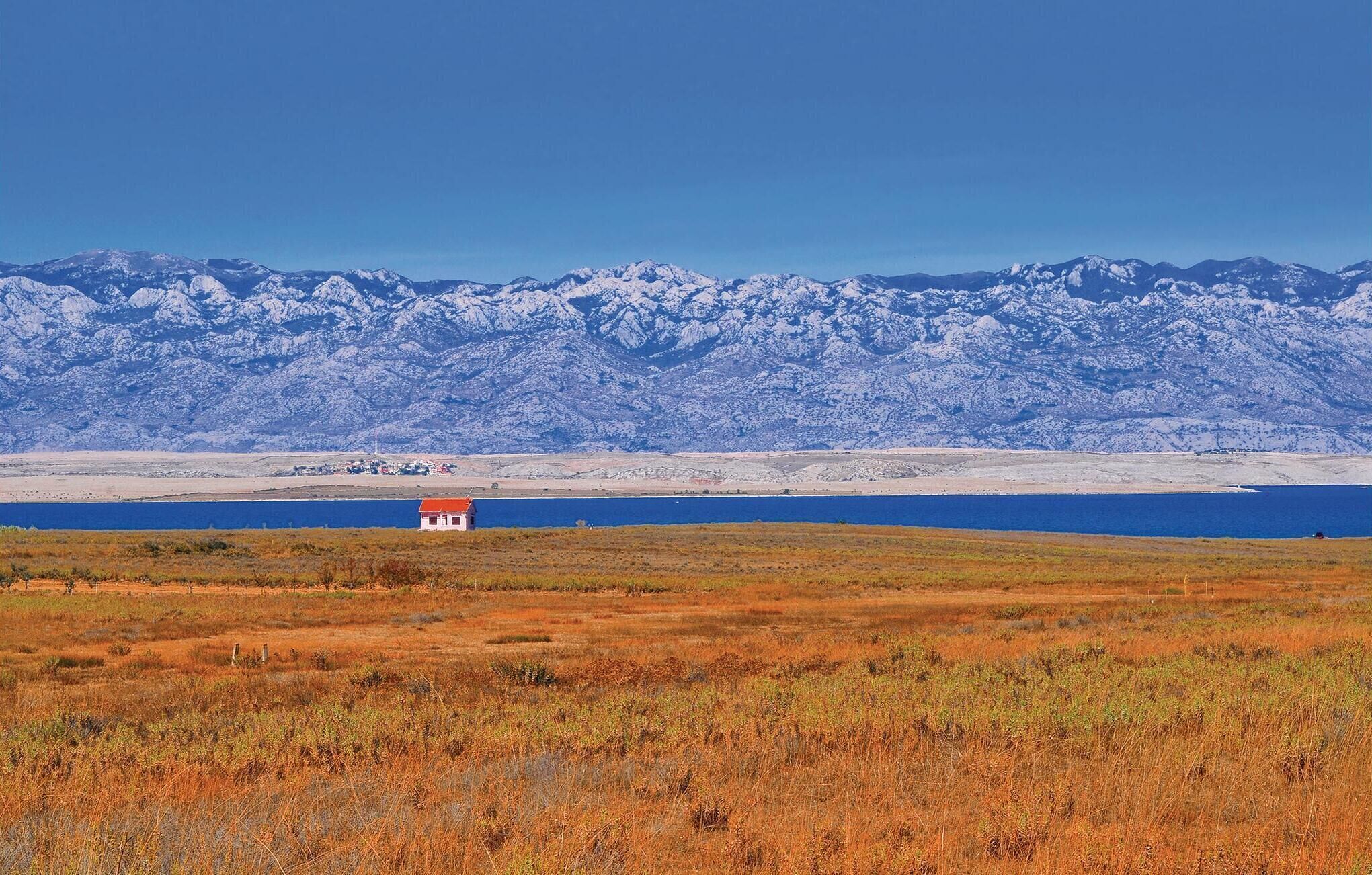 A remote, snow-capped mountain range in the background with a small building in the foreground.