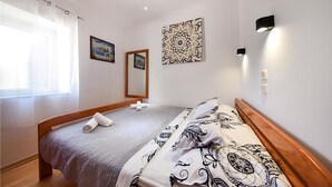 Ein ordentlich eingerichtetes Schlafzimmer mit einem Bett, einem großen Spiegel und einer Wandleuchte.