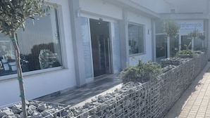 A modern building with a white facade, large windows, and a stone wall with plants. - Stella di Mare rent rooms (Civitavecchia)