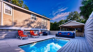 A pool area with a wooden deck, lounge chairs, and a covered seating area. - Island Adventures Await at the Pet Friendly “Boathouse SGI” (Saint George Island)