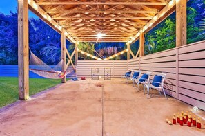 A covered outdoor area with a hammock, lounge chairs, and a ping pong table.