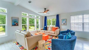 A spacious living room with a beige sofa, a blue armchair, and a colorful rug. - Island Adventures Await at the Pet Friendly “Boathouse SGI” (Saint George Island)