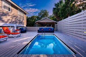 A swimming pool with lounge chairs and a covered seating area.